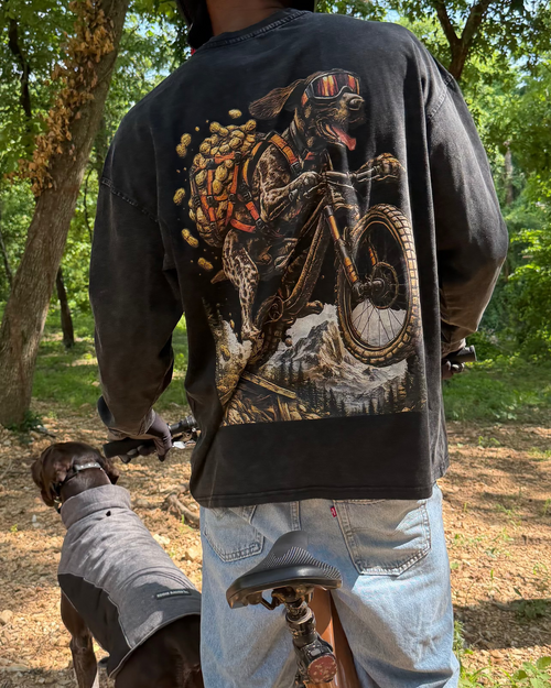 Person on a bike with a dog, both in a forest setting